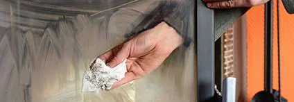 Person reinigt Kamin mit Tuch